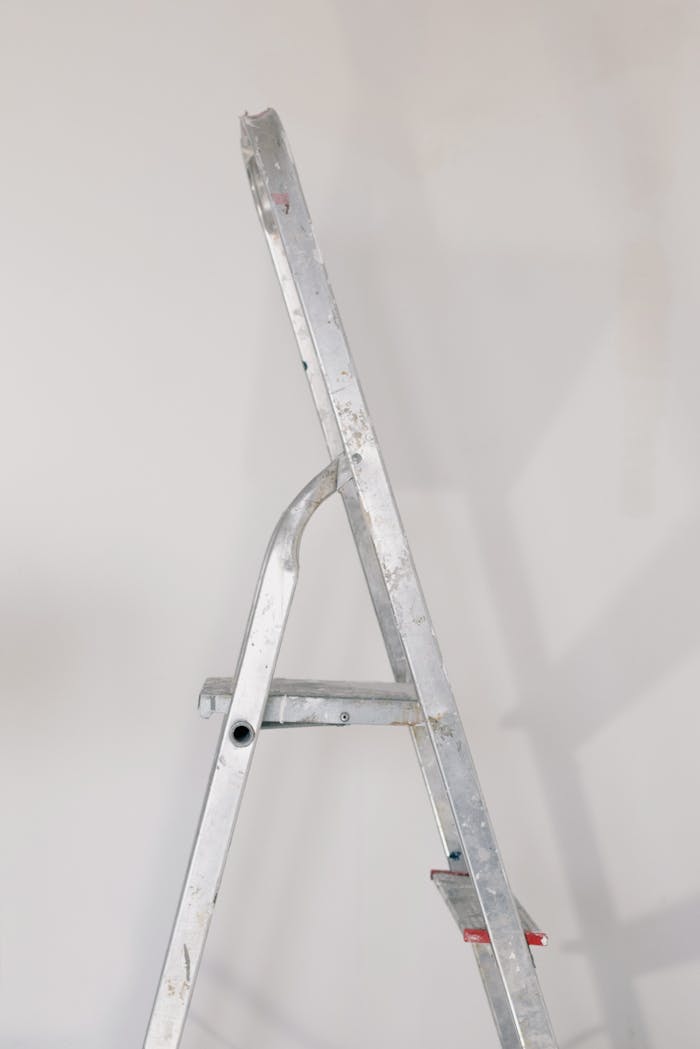 Metallic step ladder on floor against white wall in room during repair works